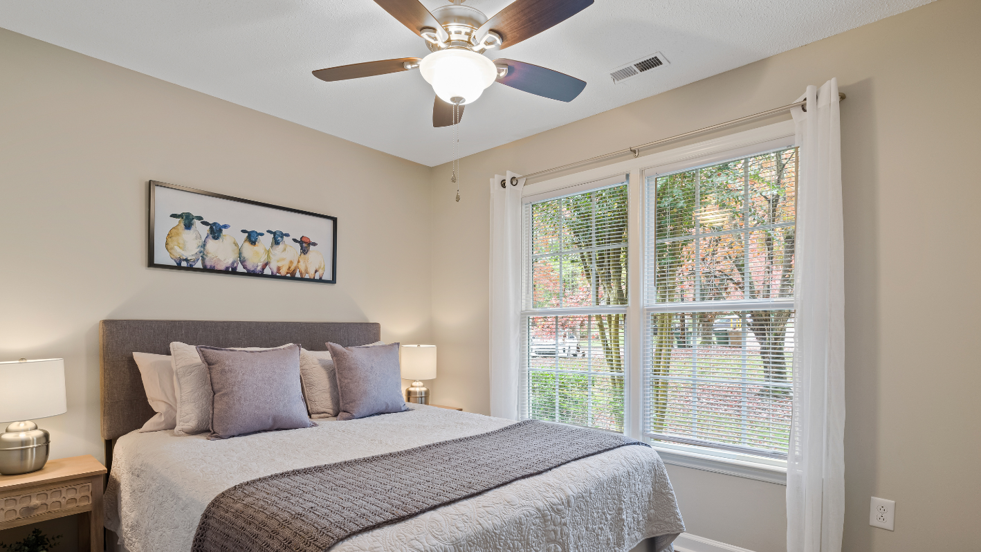 A bedroom with a bed and a ceiling fan