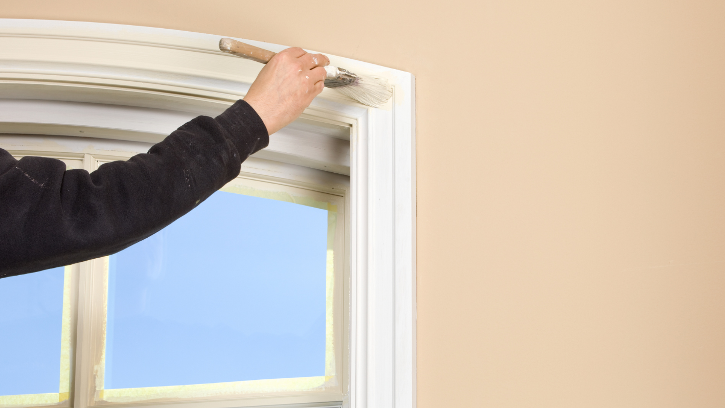 A man is painting a window with a paint roller