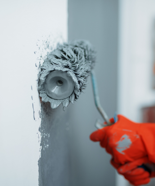 A person using a paint roller to paint a wall