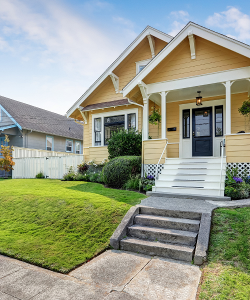 A yellow house with steps leading to the front door