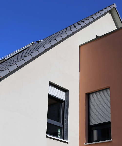 A white building with two windows and a sky background