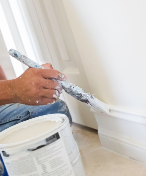 A man is painting a wall with a paint roller